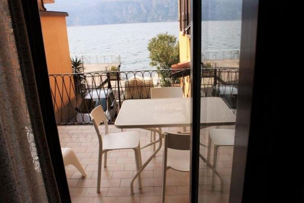 una mesa y sillas en un balcón con vistas al agua en Ferienwohnung für 5 Personen ca 65 qm in Malcesine, Gardasee Ostufer Gardasee, en Malcesine