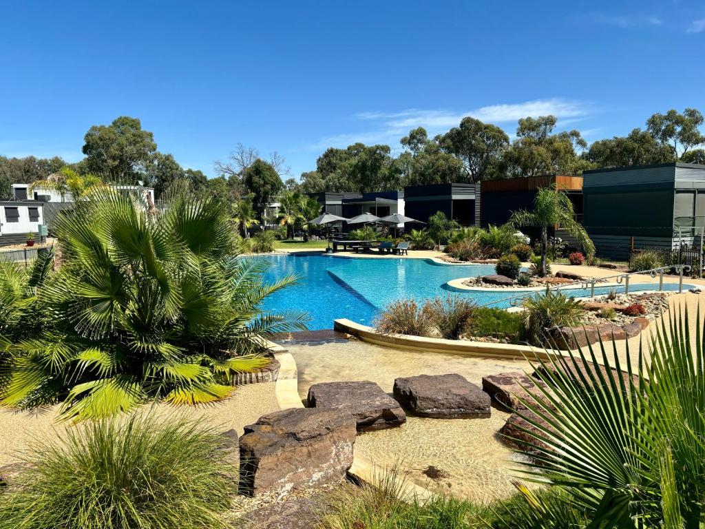 ein Pool in einem Resort mit Bäumen und Felsen in der Unterkunft Stunning Lakeside Villa in River Front Resort with Pool in Moama