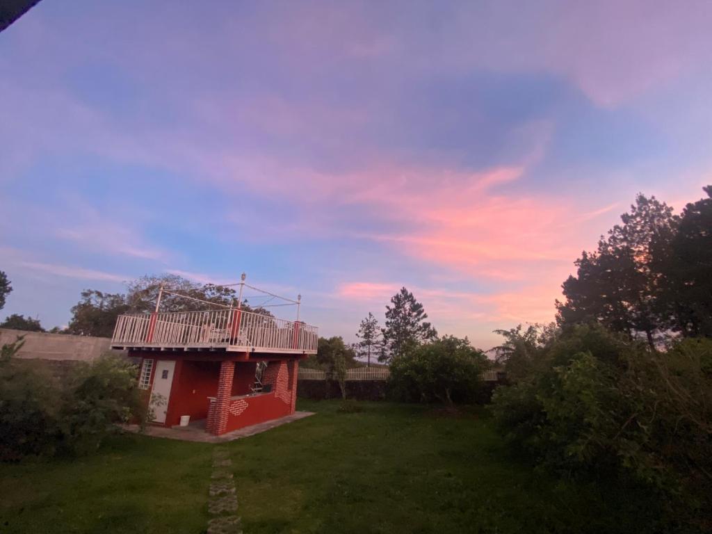 un piccolo edificio rosso con tetto su un campo di Volcano Pines Retreat ad Alto Boquete