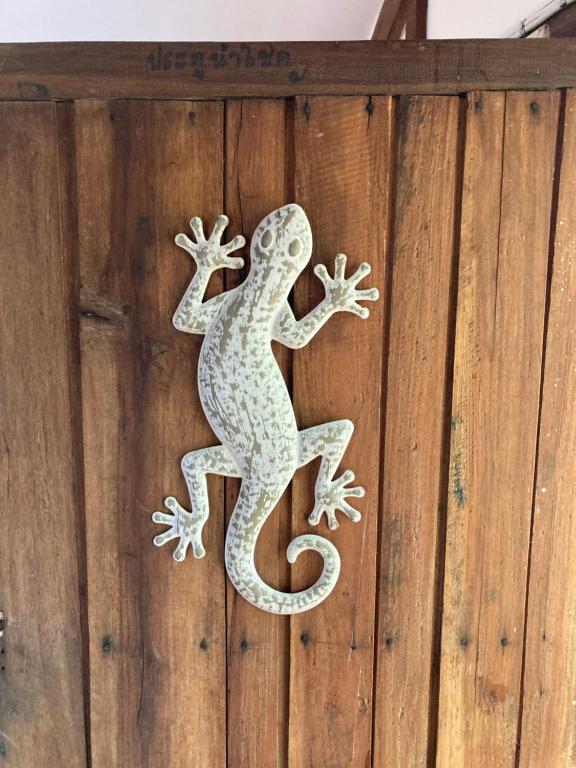 um lagarto no lado de uma parede de madeira em Udon Thani Farm Stay Talay Bua Daeng em Ban Non Sung