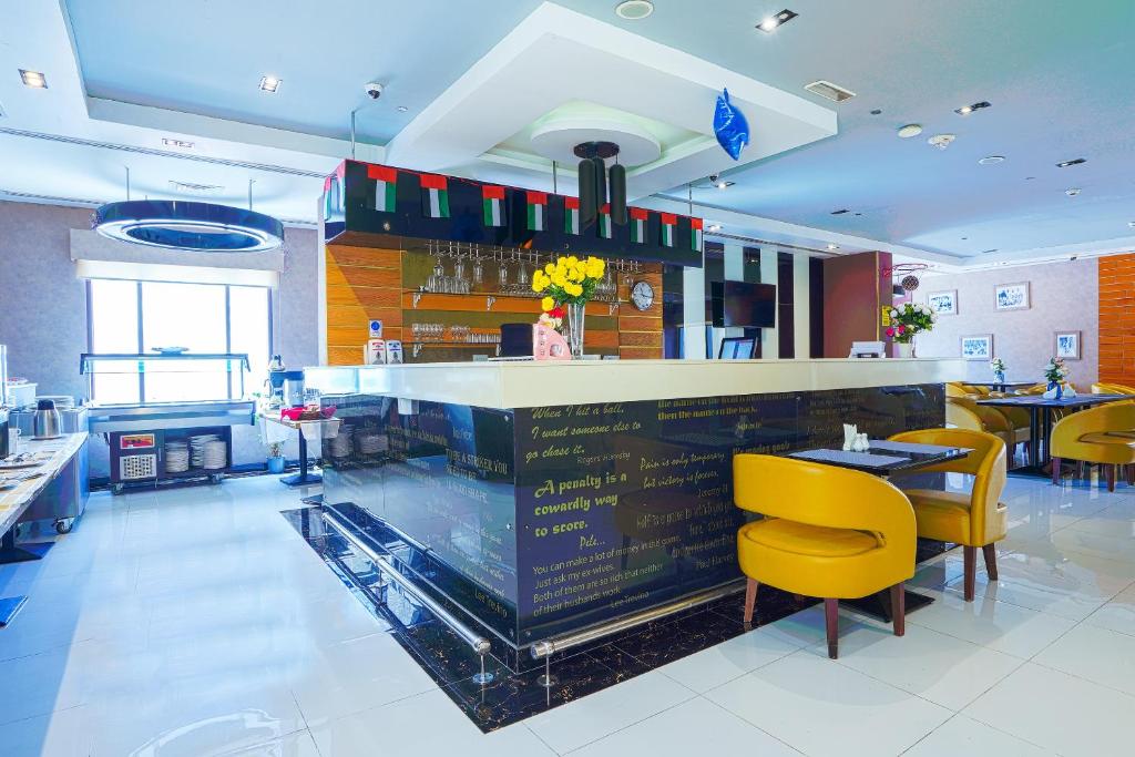Palette Royal Reflections Hotel and Spa Dubai في دبي: مطعم فيه بار بالكراسي الصفراء والطاولات