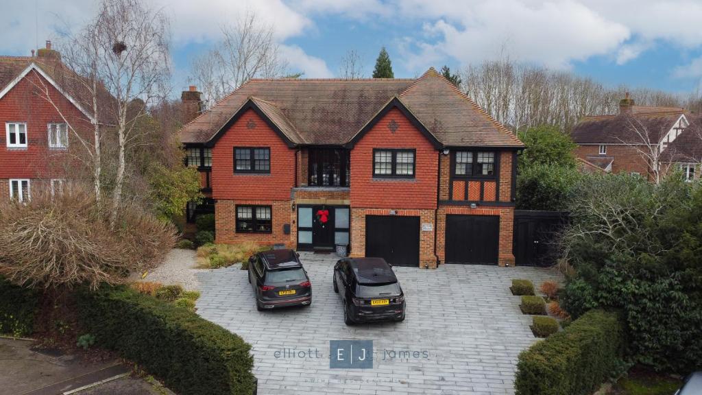 two cars parked in a parking lot in front of a house at Grand London suburban mansion in Buckhurst Hill