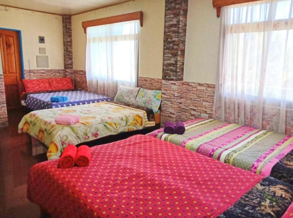 una habitación con 3 camas con zapatos rojos. en An Escape to a Semi-Countryside Retreat - SEE TOO VILLE- Nature Lodging Home, en Sagada