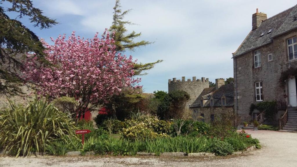 einen Garten vor einem Schloss mit einem blühenden Baum in der Unterkunft Les Chambres du Château du Rozel in Le Rozel