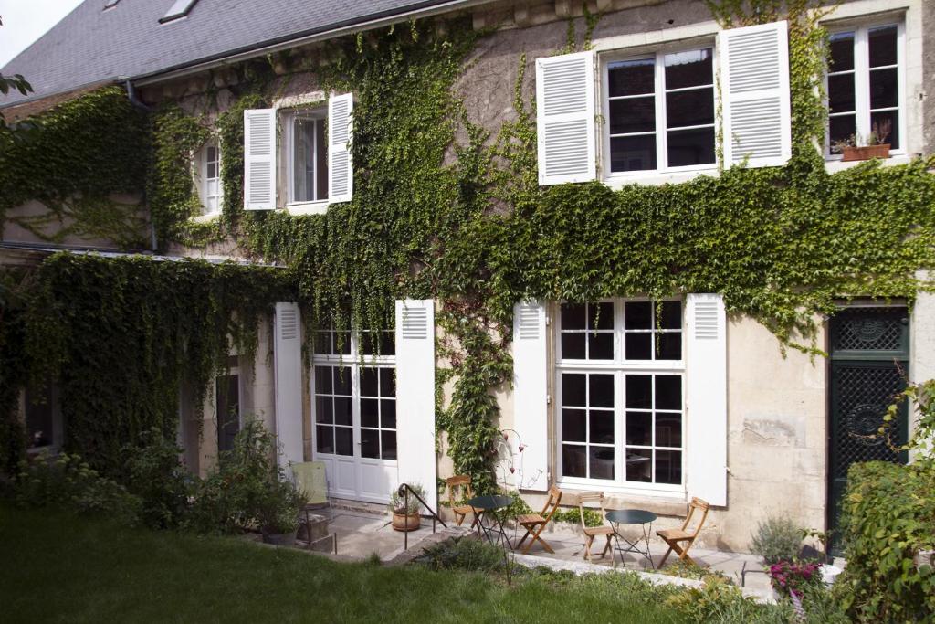 an ivy covered house with chairs and tables in front of it at La Maison Saint Aignan in Saint-Aignan