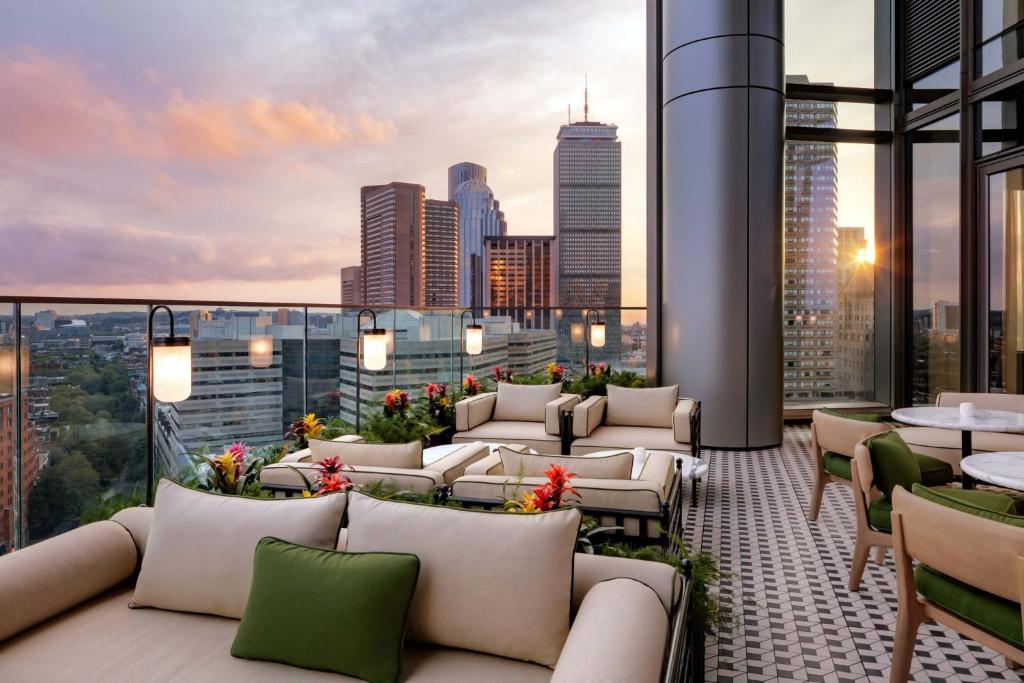 eine Dachterrasse mit Sofas und Tischen und eine Skyline der Stadt in der Unterkunft Boston West End Penthouse Edition in Boston