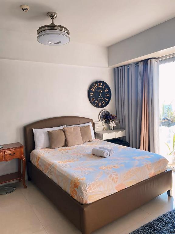 um quarto com uma cama com um relógio na parede em Palm Tree Villas - STUDIO UNIT em Manila