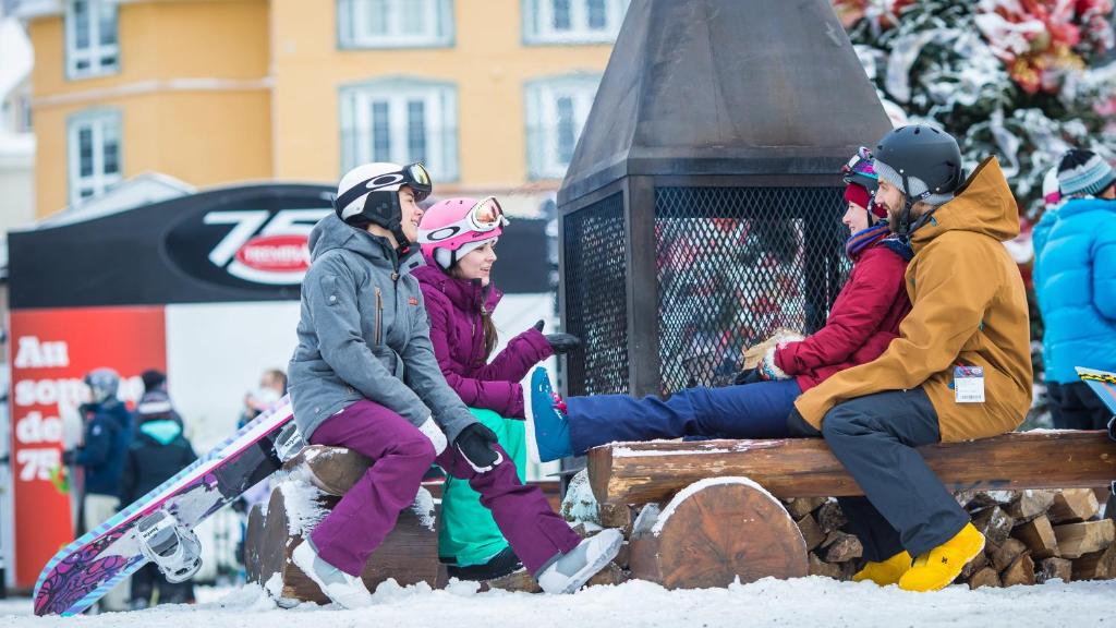 Un groupe de personnes assises sur un banc dans la neige dans l'établissement Holiday Inn Express & Suites Tremblant, an IHG Hotel, à Mont-Tremblant