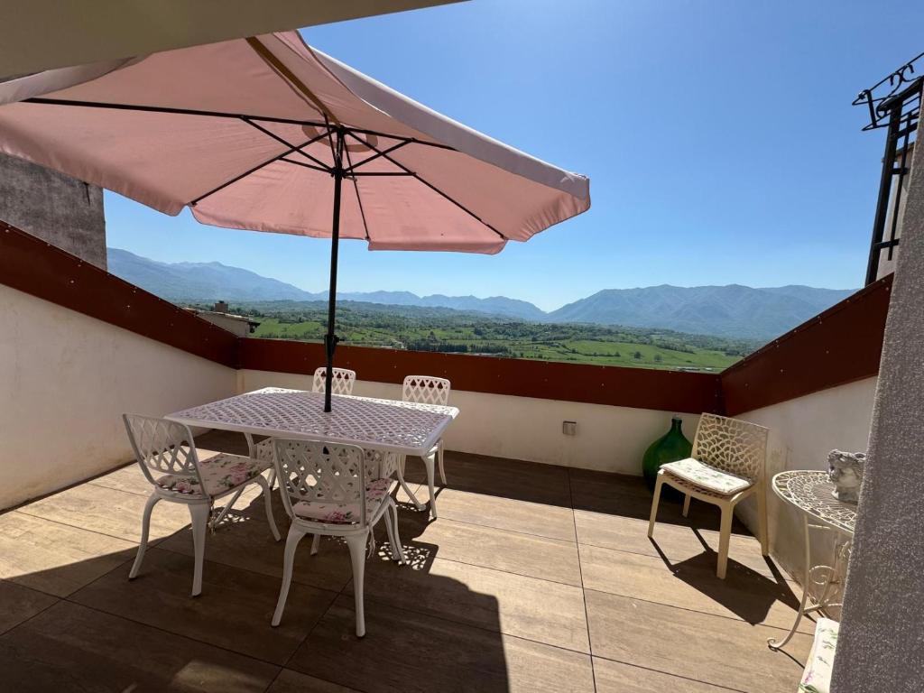 un patio con mesa, sillas y sombrilla en La Casa di Nathalie, en Alvito