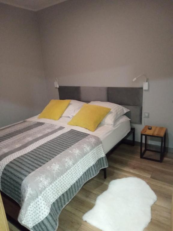 1 dormitorio con 1 cama grande con almohadas amarillas en Apartamenty Jana Pawła en Uniejow