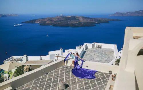 a woman in a blue dress standing on top of a building at Beautiful Santorini Villa | Villa Galázio | 2 Bedrooms | Private Terrace & Breathtaking Caldera Views | Fira in Fira