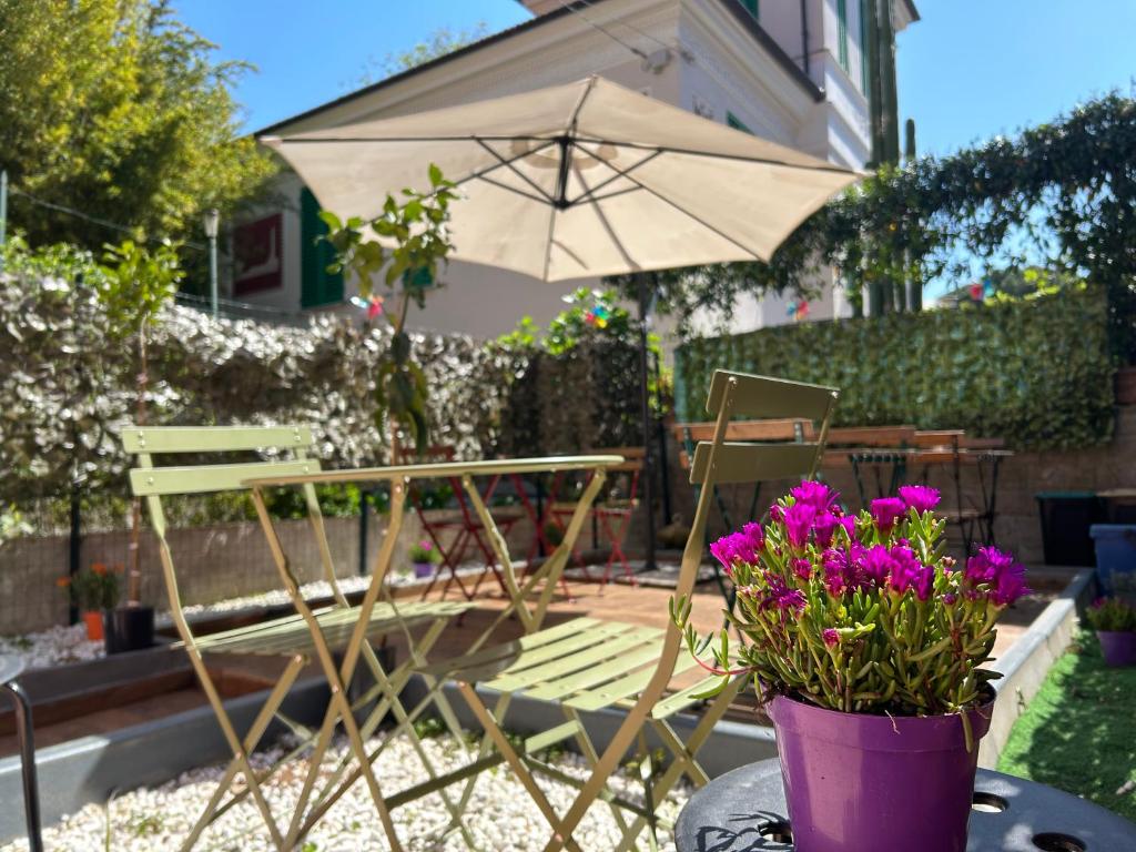 a patio with a table and an umbrella and flowers at Pink House Garden in Monterosso al Mare