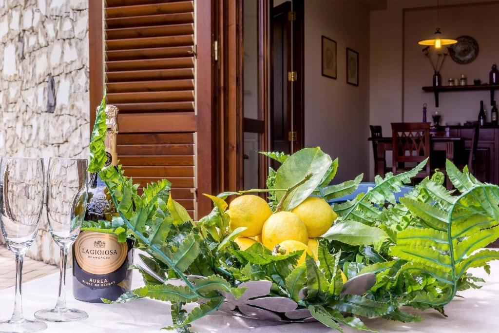 un tavolo con un mazzo di limoni e una bottiglia di vino di Ferienwohnung für 2 Personen 2 Kinder ca 50 qm in Taormina, Sizilien Ostküste von Sizilien a Taormina