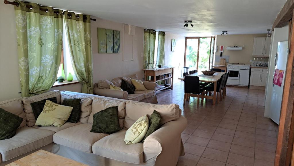 a living room with two couches and a kitchen at Les Bigoussies in Ribérac