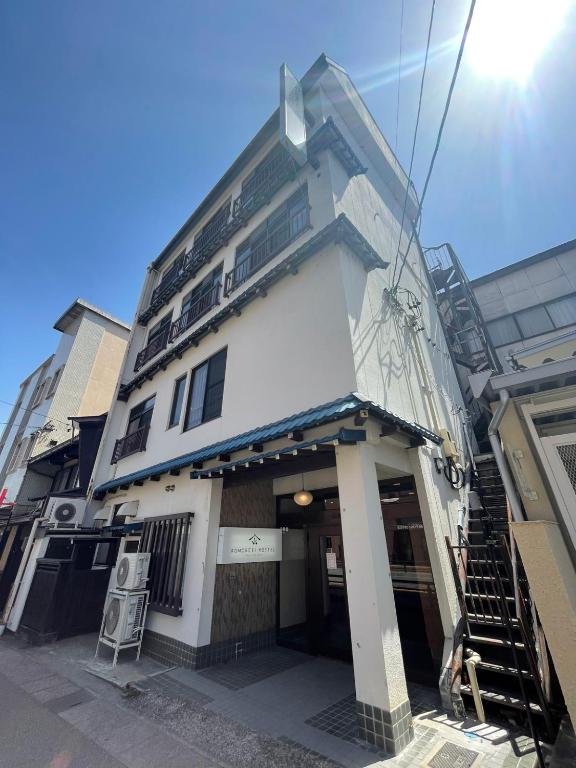 a tall white building with a stairway in front of it at KOMOREBI HOSTEL-your cozy place- in Takayama