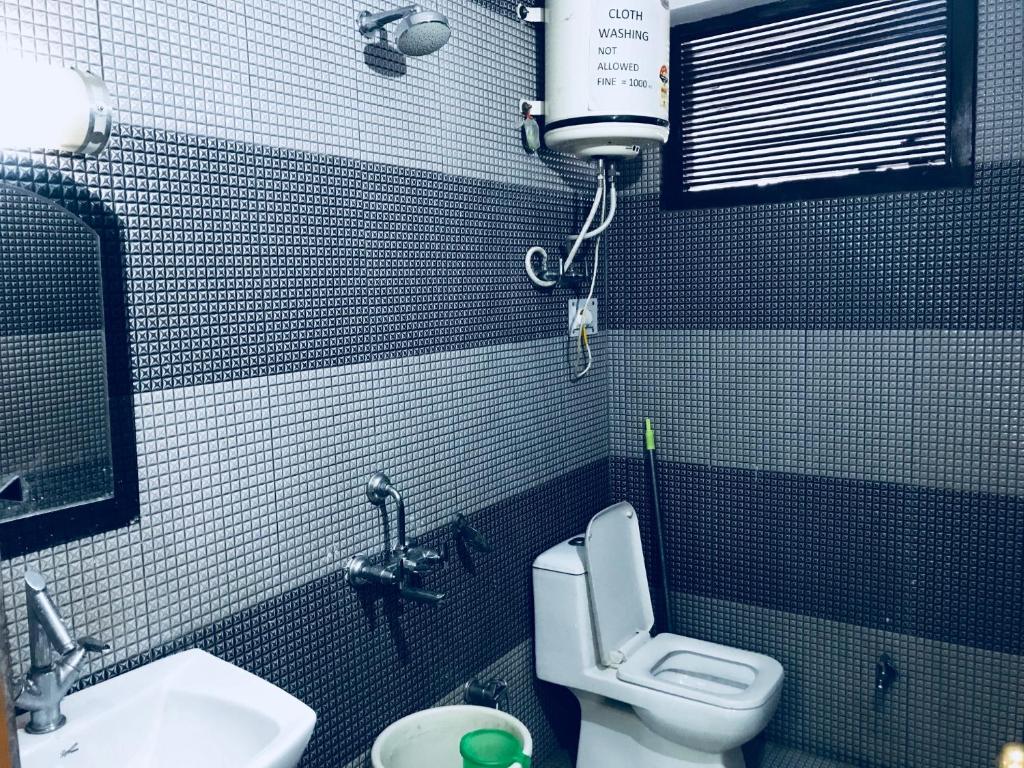 a small bathroom with a toilet and a sink at DevDham Lodge in Chandīgarh