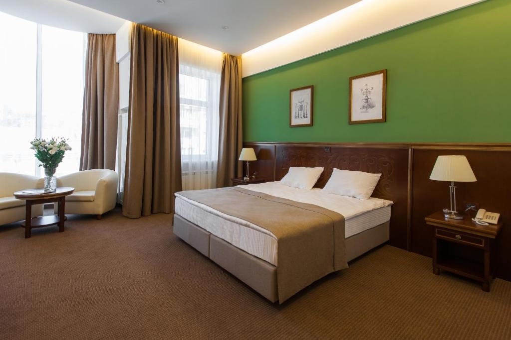 Habitación de hotel con cama y pared verde en Alarus Luxe Hotel, en Odessa