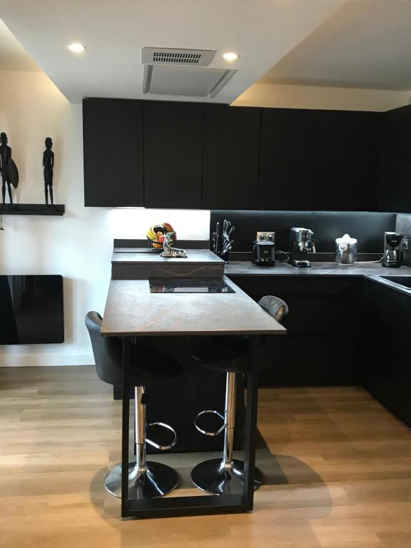 uma cozinha com armários pretos e uma mesa de madeira em Appartement de luxe urrgne em Urrugne