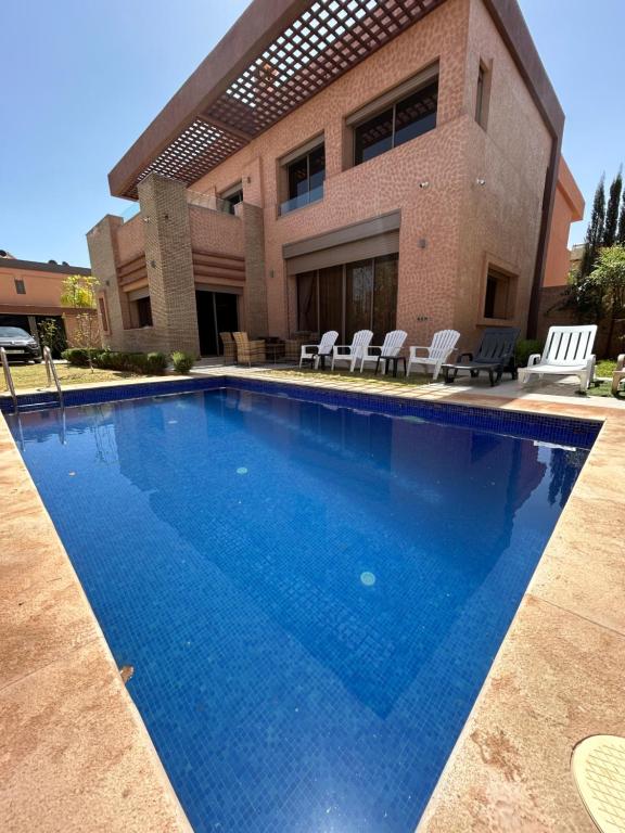 une grande piscine bleue en face d'une maison dans l'établissement Villa djelloul, à Marrakech