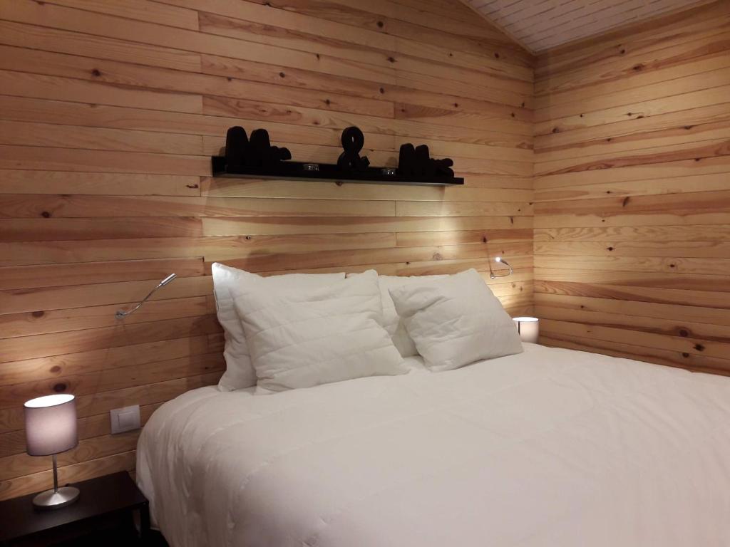 a bedroom with a white bed in a wooden wall at Woody Lodge - Duplex Nature Bonsoy Ardennes in Hastière-par-delà