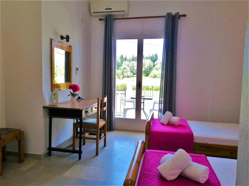 a room with a bedroom with a desk and a table at Nikos Apartments 1 in Kavos