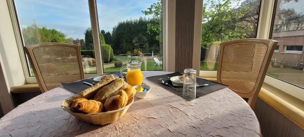 a table with a basket of bread and orange juice at Hôtel Côté Jardin in Commercy