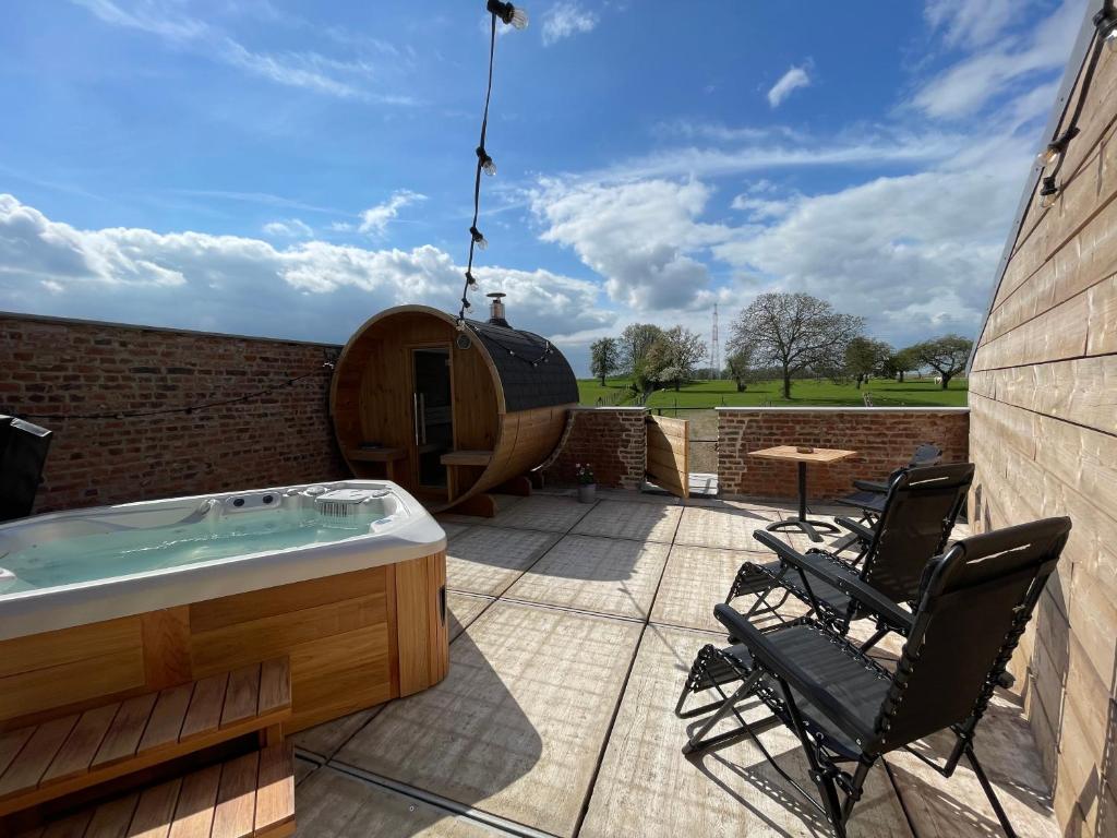 a hot tub on a patio with two chairs at Boven de paarden @ de Hoeveschuur in Riemst