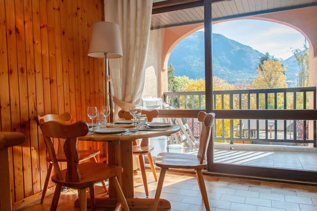 une salle à manger avec une table et des chaises et une grande fenêtre dans l'établissement Briançon studio à seulement 200m des pistes !, à Briançon
