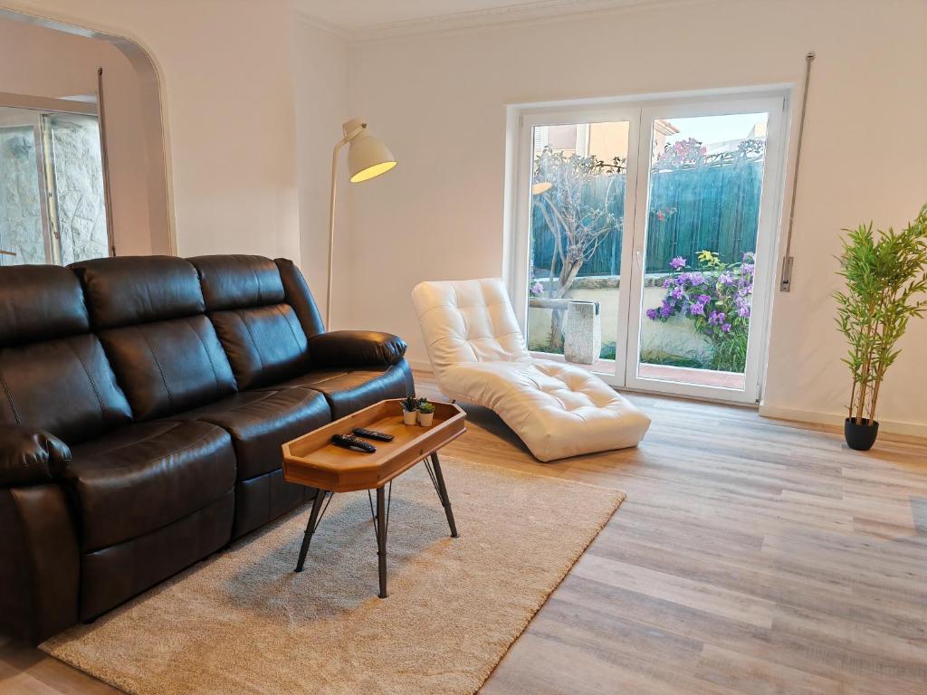 a living room with a leather couch and a table at Villa dos castanheiros in Cascais