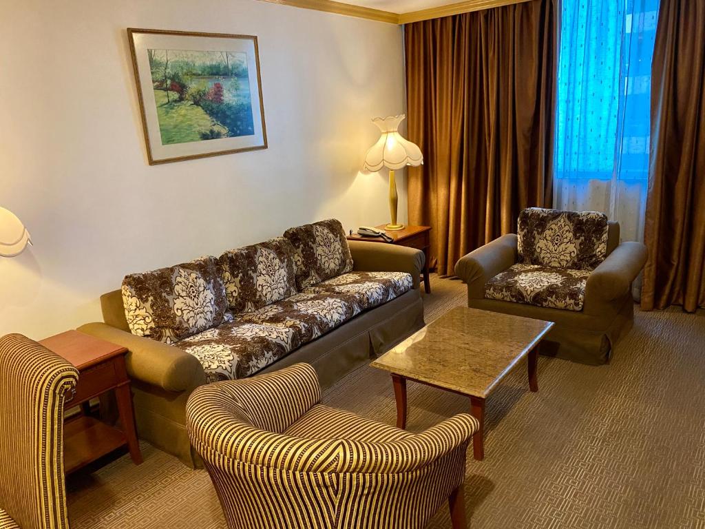 a living room with a couch and chairs in a hotel room at Maharaja Oriental Suite Makati in Manila