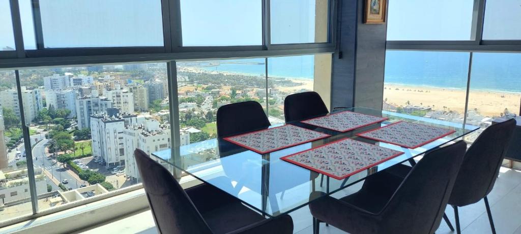 a dining table with chairs and a view of the ocean at Luxury open-space apartments by the sea in Ashdod