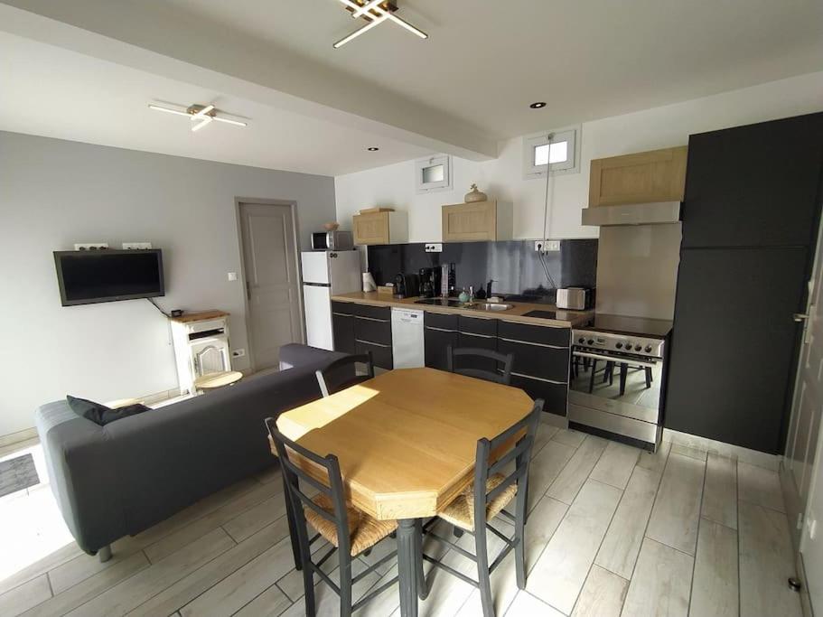 une cuisine avec une table en bois et un canapé dans l'établissement La Chaloupe gites de mer, à Jullouville