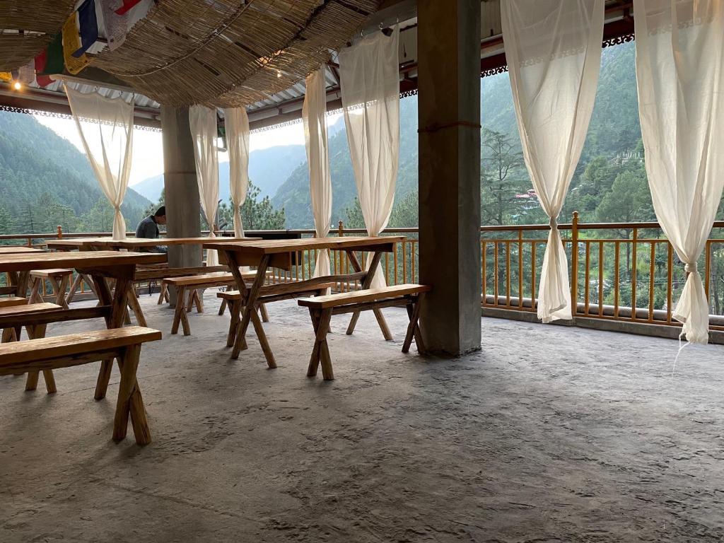a room with wooden tables and benches on a balcony at Highland spirit 2 in Kasol