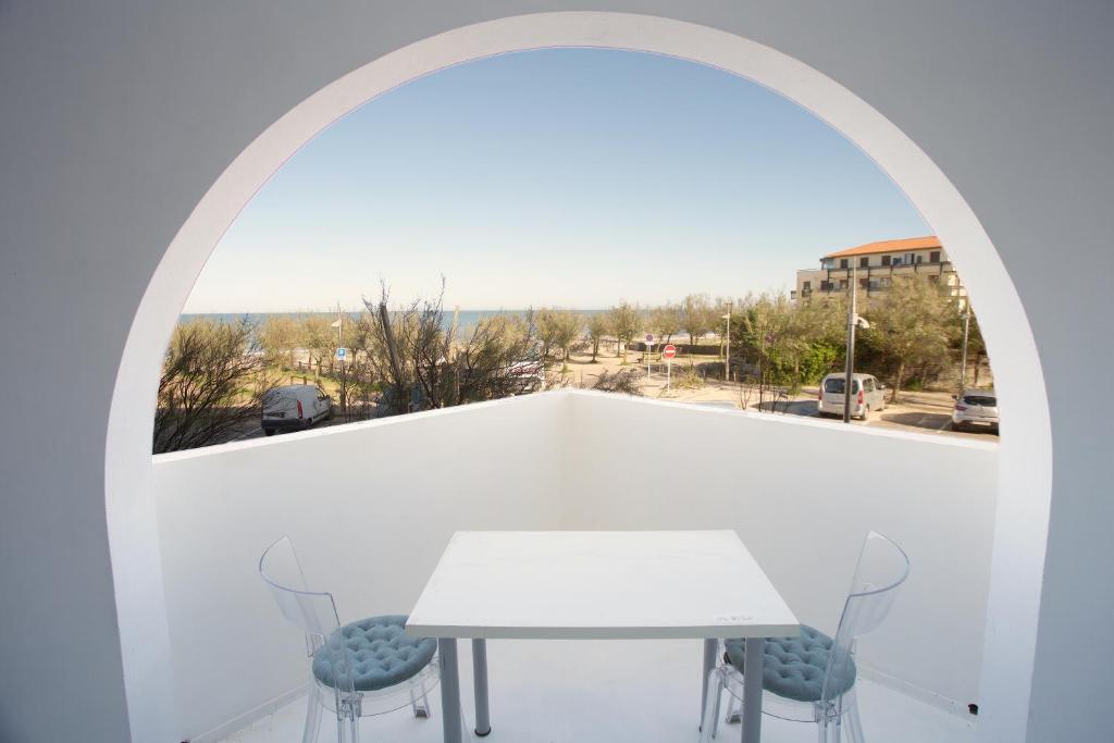 ein weißes Zimmer mit einem Tisch, Stühlen und einem Fenster in der Unterkunft Hossegor - Vue Océan - Plage - Couple - Enfant in Soorts-Hossegor