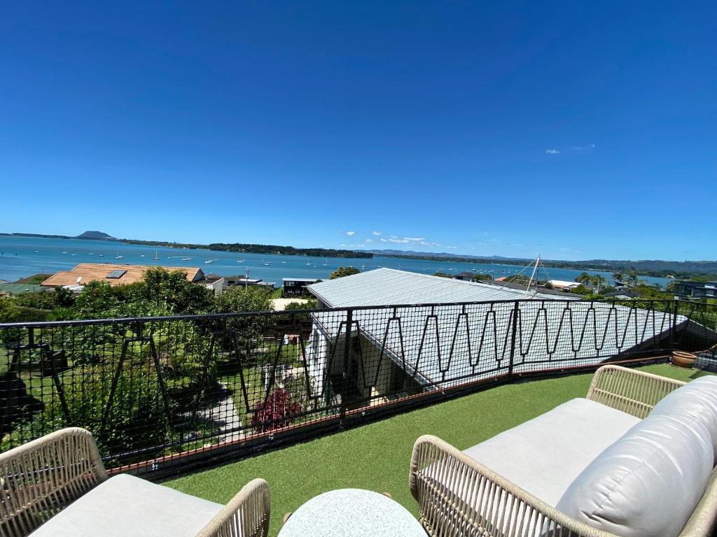 a balcony with chairs and a view of the water at The Views - Omokoroa in Omokoroa