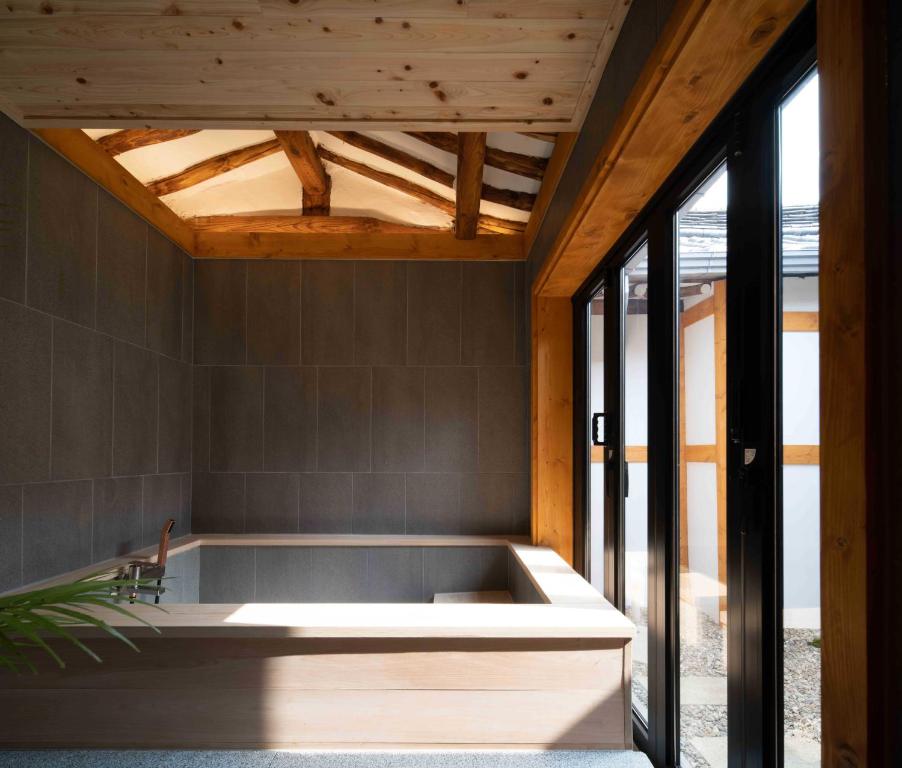 uma banheira no meio de um quarto com janelas em Luxury hanok with private bathtub - SW02 em Seul