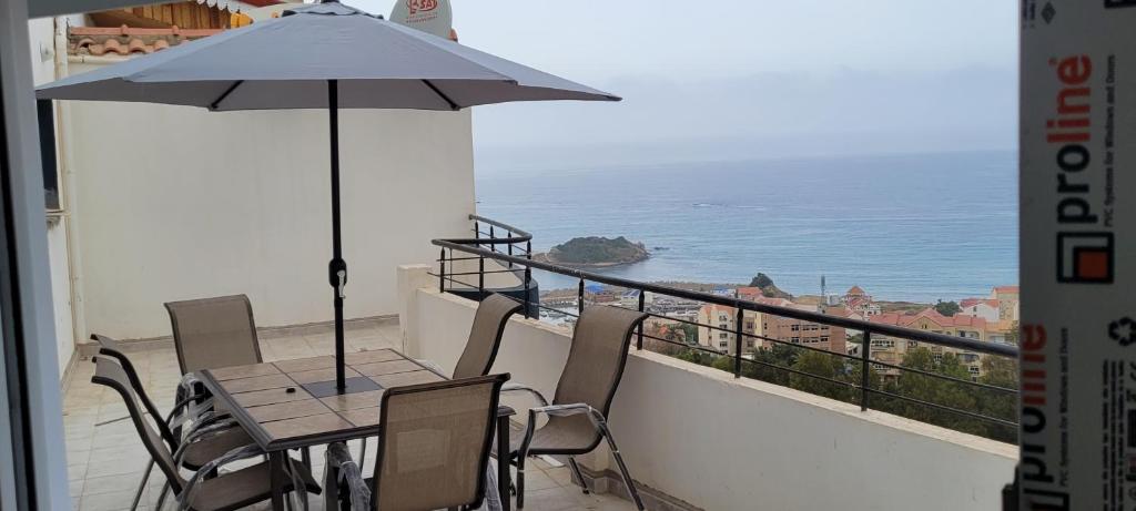 a table with an umbrella on a balcony with the ocean at Immeuble Thala Duplex 135 m² in Tigzirt