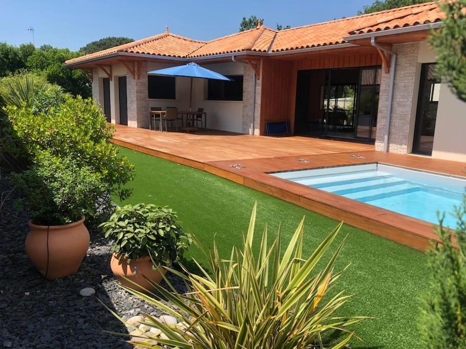 une cour avec une piscine et une maison dans l'établissement Belle maison avec piscine chauffée Lège Cap Ferret, à Lège-Cap-Ferret