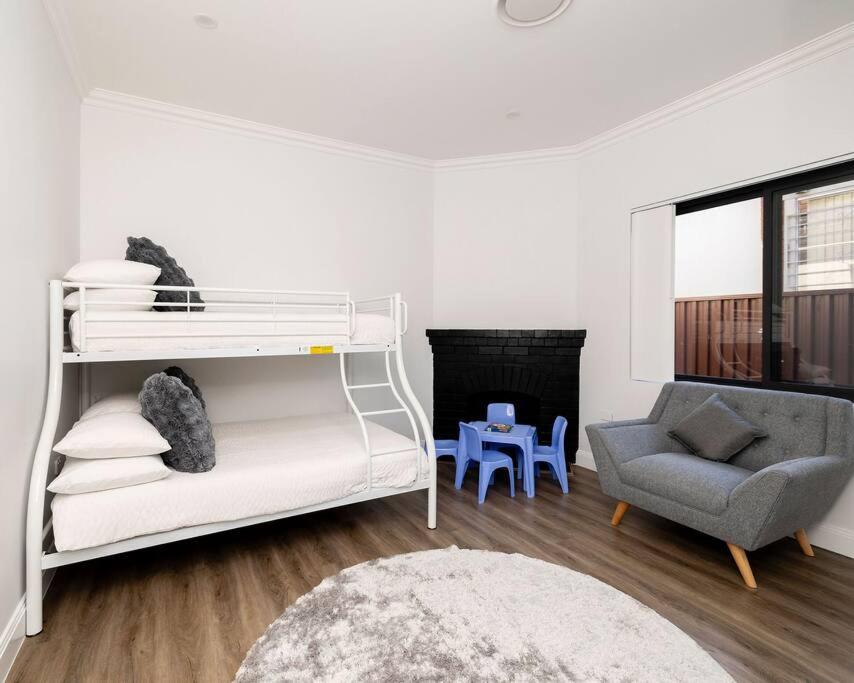 a white room with a bunk bed and a chair at Modern Home in the Heart of Bankstown in Bankstown