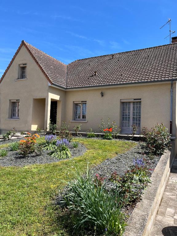 une maison fleurie dans la cour avant dans l'établissement Spacieuse maison de village, à Luché-Pringé