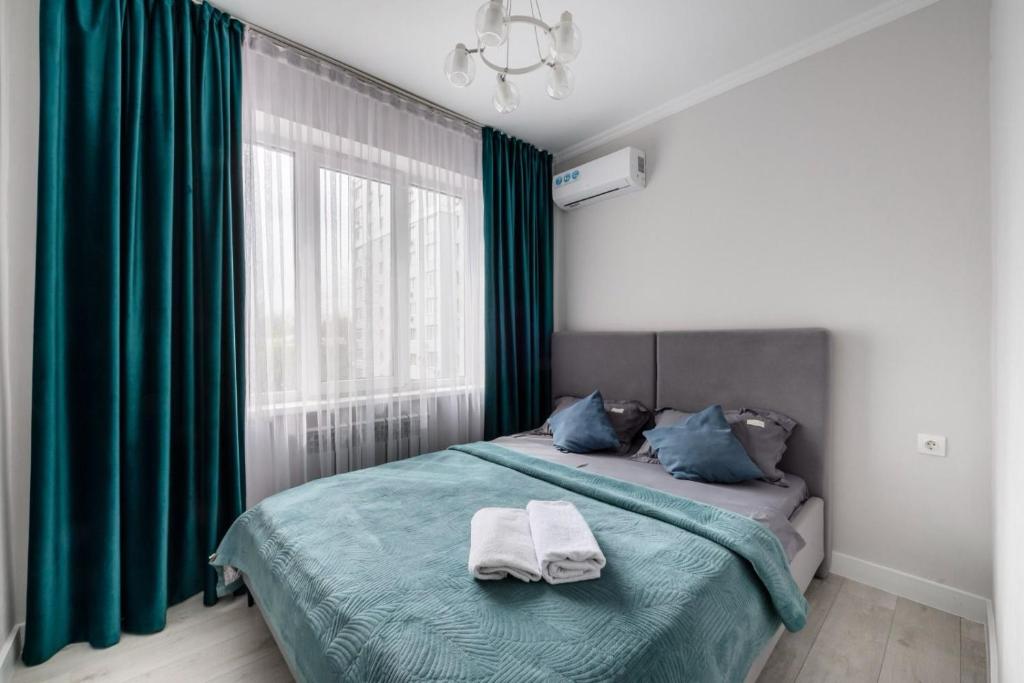 1 dormitorio con 1 cama con cortinas verdes y ventana en Атлантическая бриза en Almaty