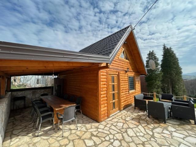 a wooden cabin with a table and chairs on a patio at Jerry's Cottage Banja Luka in Banja Luka