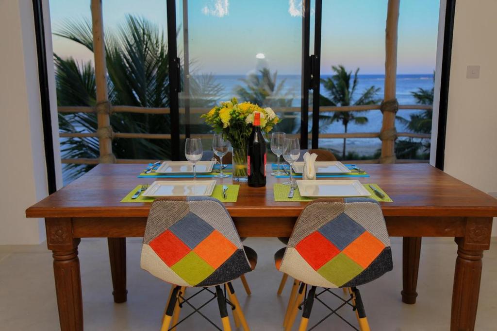 a wooden table with two chairs and a vase of flowers at Ahadi Homes in Mombasa