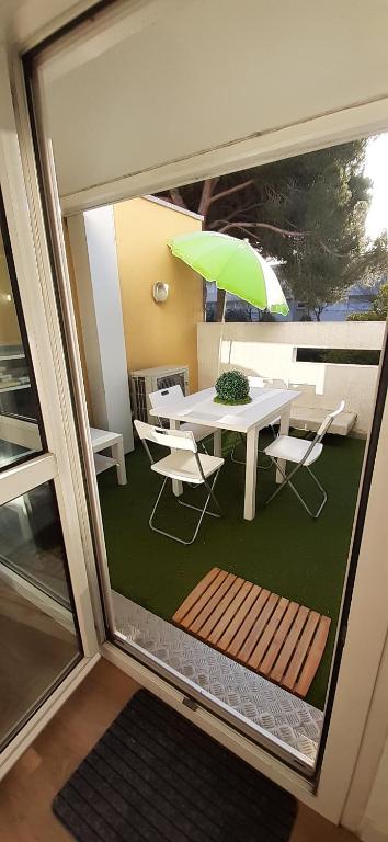 une table et des chaises avec un parasol vert dans l'établissement T2 à 2 pas du centre-ville, à La Grande Motte
