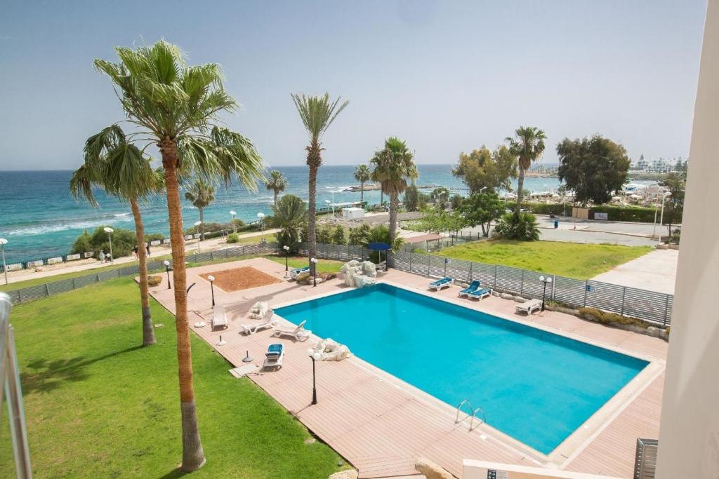 una piscina con palmeras y el océano en Ferienwohnung für 7 Personen ca 90 qm in Protaras, Südküste von Zypern en Protaras