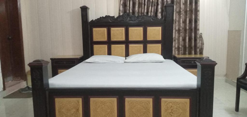 a bed with a wooden frame and white sheets at Decent Palace in Lahore