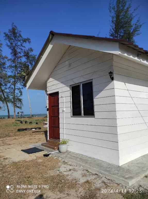 una pequeña casa blanca con una puerta roja en Chalet Bonjour, en Bachok