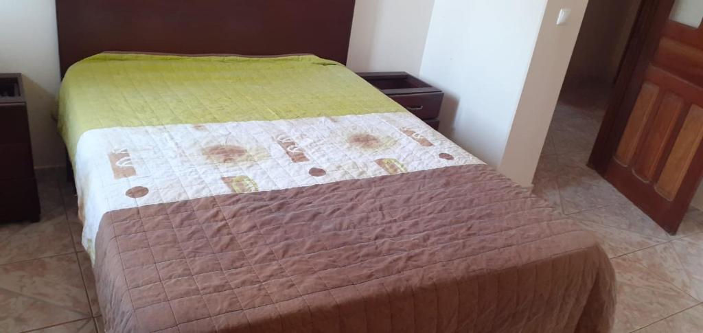een bed in een kamer met een groene deken erop bij 2 chambres d’hôtes in Tarrafal