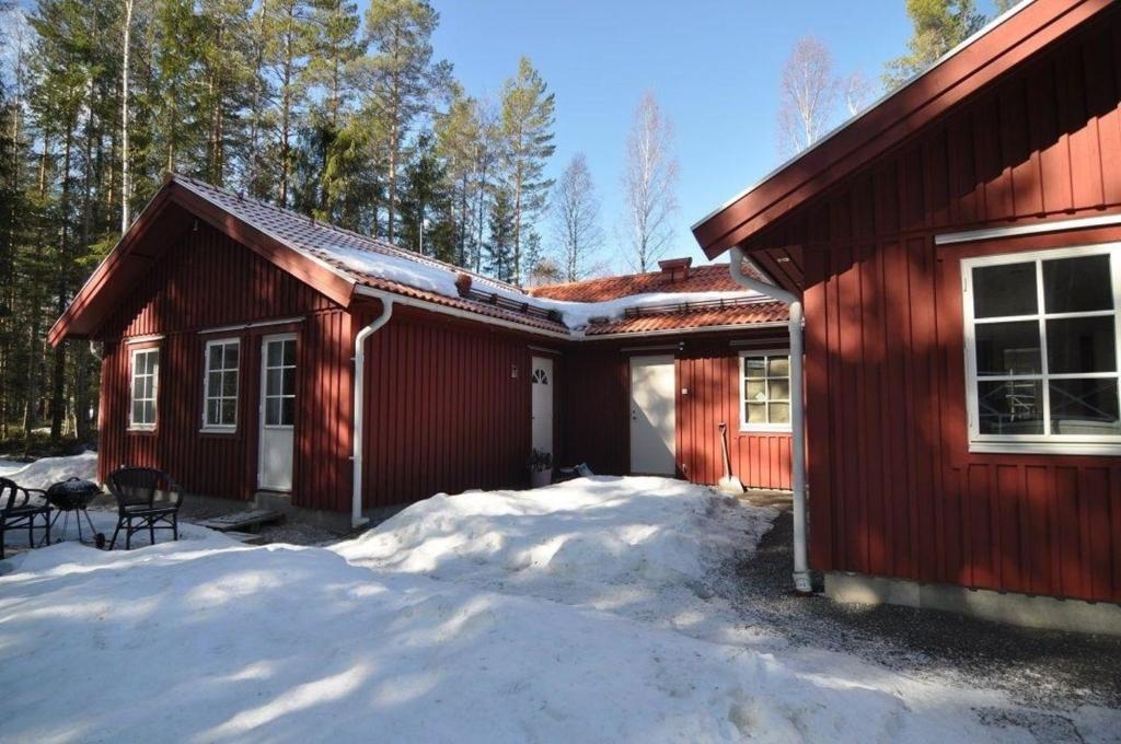 una casa rossa con la neve davanti di Ferienwohnung für 5 Personen ca 60 qm in Borlänge, Mittelschweden See Runn a Borlänge