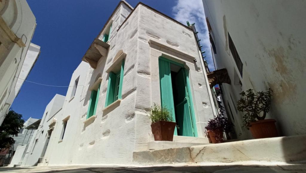 a white building with green doors and windows at Παραδοσιακό Σπίτι στον Πύργο in Panormos